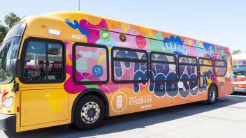 A colorful Unitrans bus wrapped with a bright design promoting the UC Davis "Moo-vin' Moo-seum."